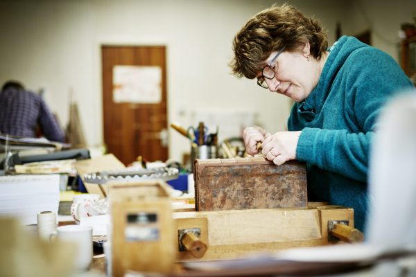 a-woman-working-at-a-bench-on-the-binding-of-a-boo-2023-11-27-04-57-55-utc