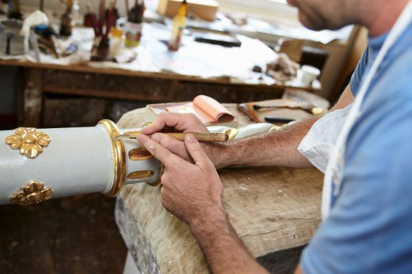 worker-applying-gold-leaf-to-pole-2024-11-03-04-31-21-utc